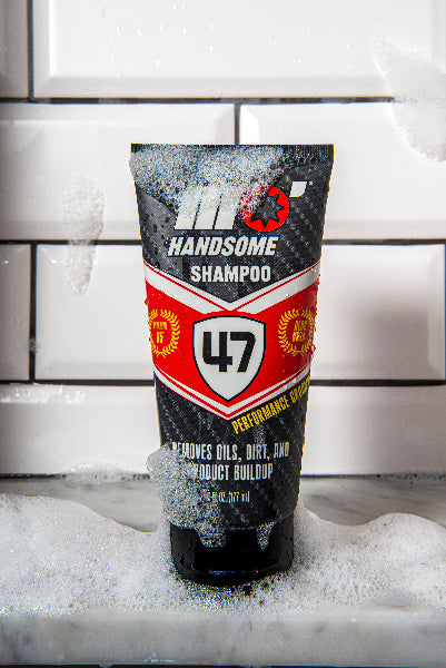 Mo’Handsome tube featuring bold red Ferrari-style design—surrounded by bubbles in a bathroom setting.