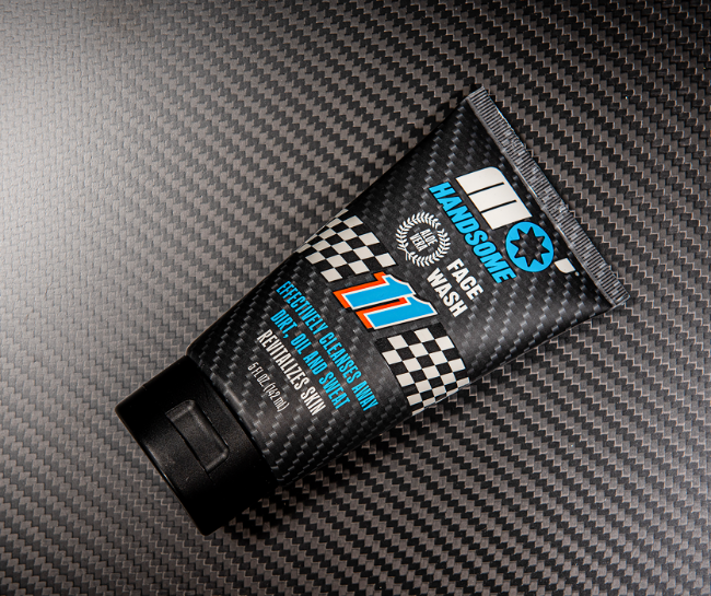 Close-up of Mo’Handsome face wash on carbon fiber surface—racing-style tube with number 11 roundel inspired by top stock car drivers.