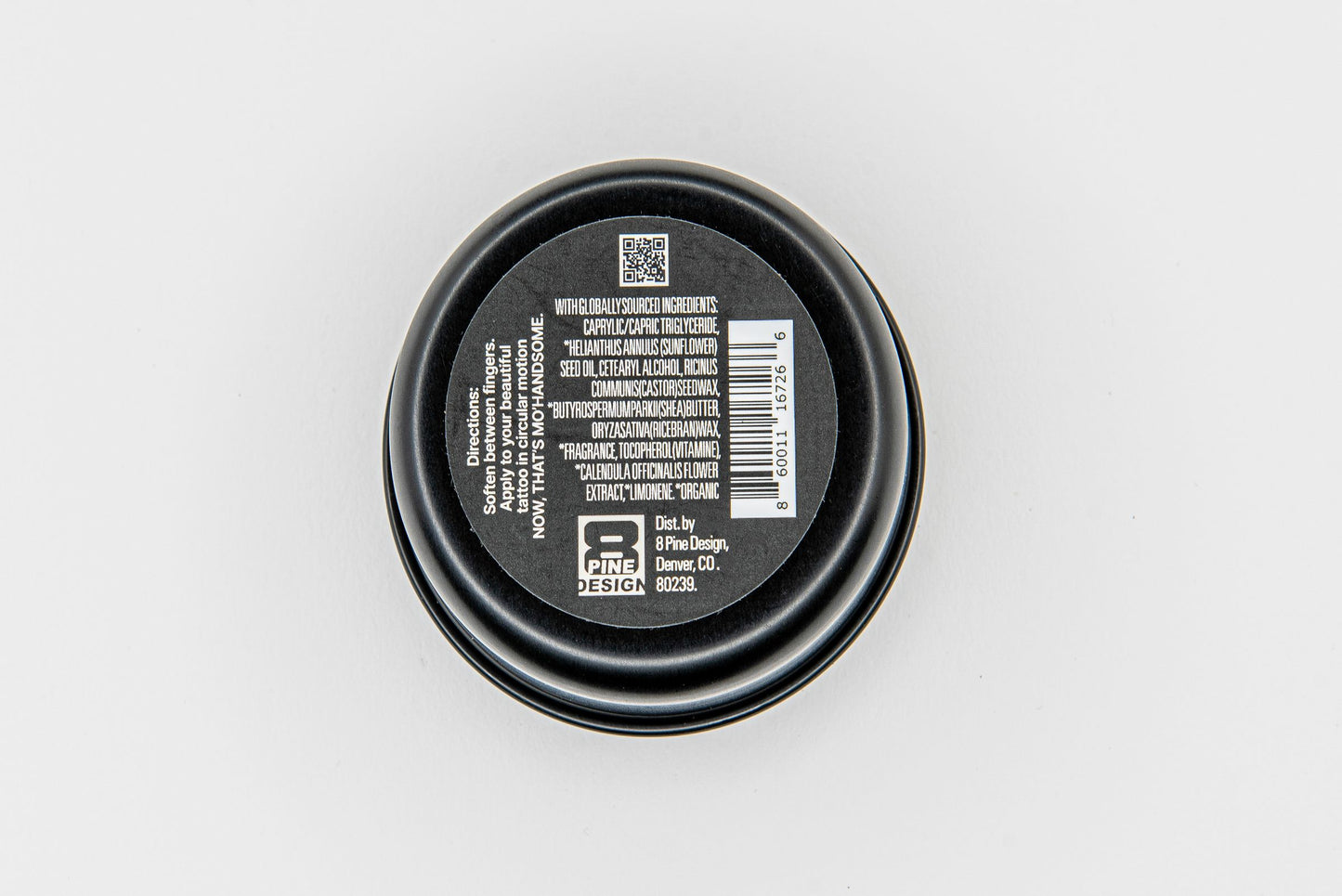 Close-up, underside view of Mo’Handsome tattoo salve tin—rugged packaging for nourishing post-ink recovery.