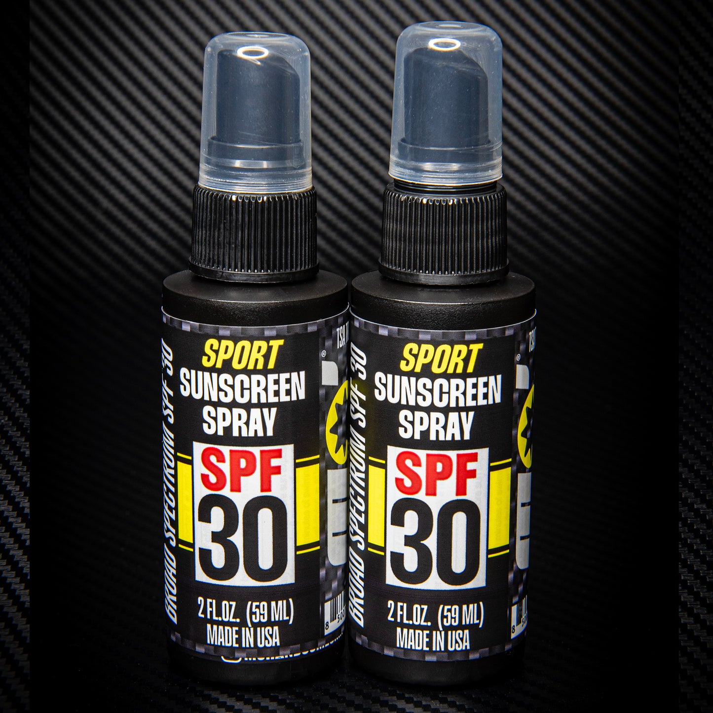 2 pack spf 30 sport sunscreen spray TSA approved standing on black carbon fiber background