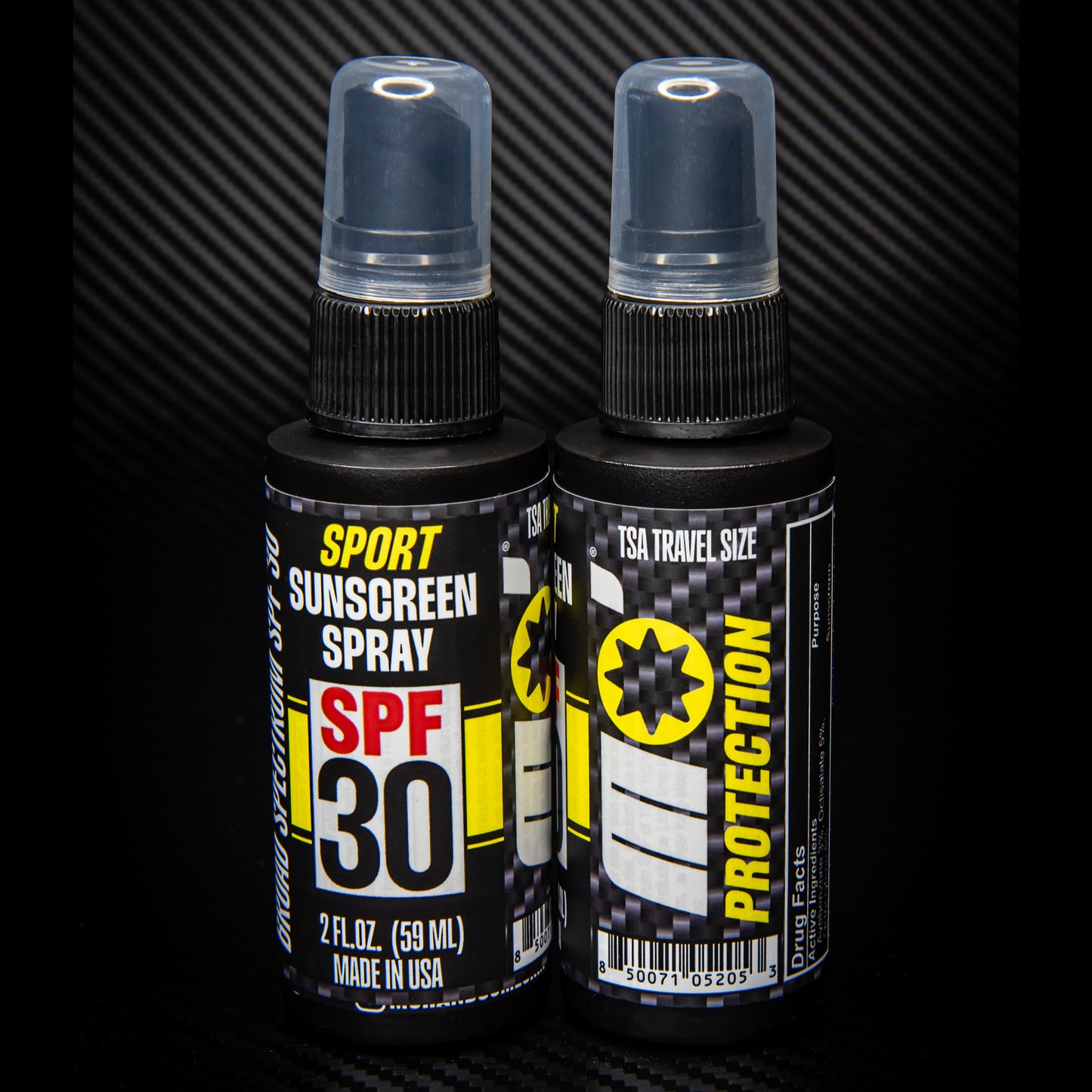 2 pack SPF 30 sport sunscreen spray TSA approved standing back to back on black carbon fiber background