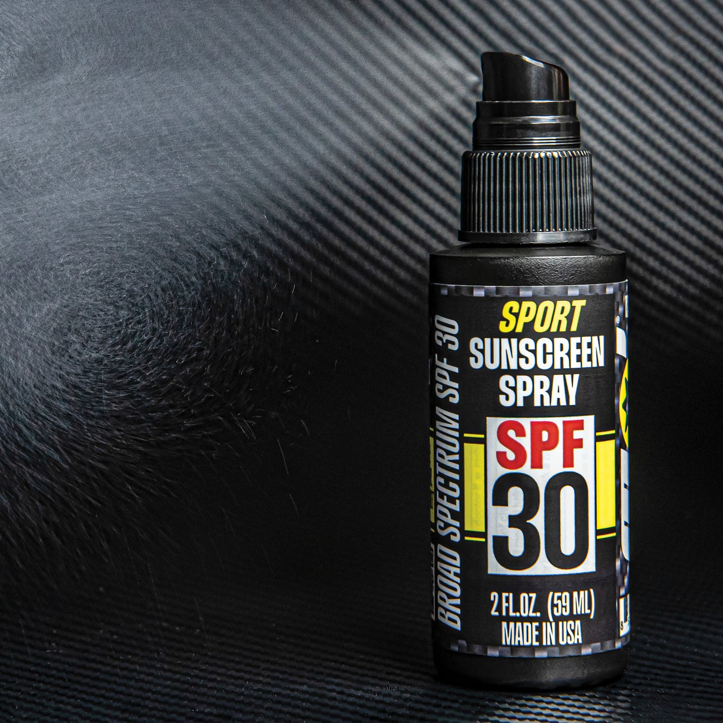Sunscreen spray bottle with SPF 30 label fine misting on carbon fiber black background