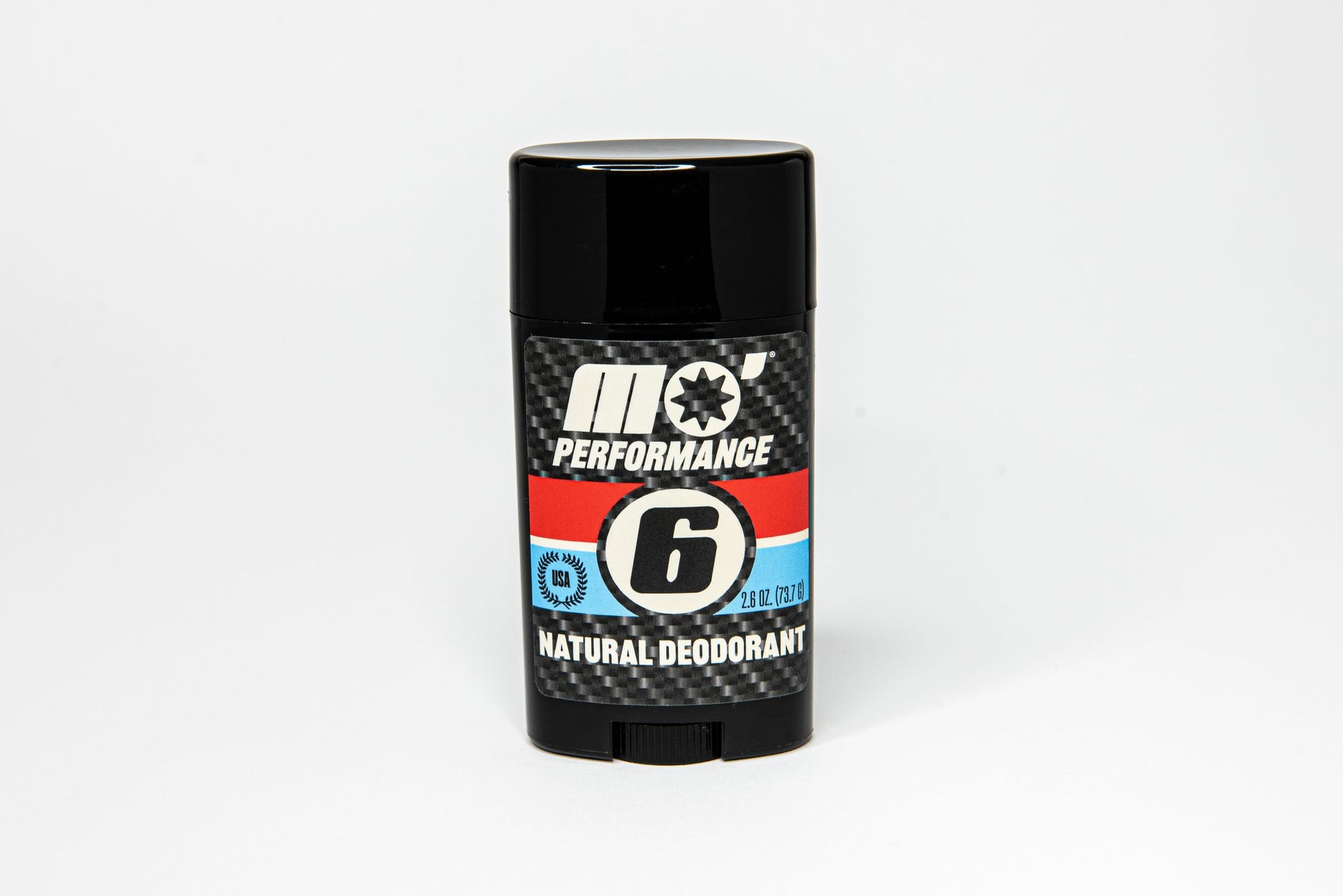 Mo’Handsome Mo’ Performance natural deodorant standing upright with No. 6 roundel and carbon fiber look—bold design, all-day freshness.