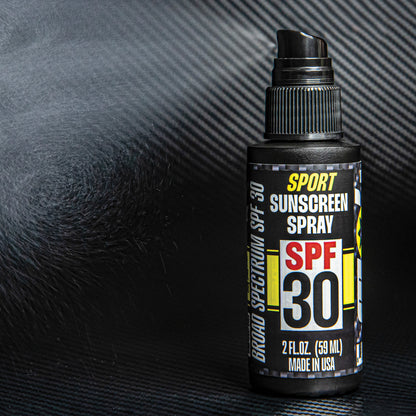 Sunscreen spray bottle with SPF 30 label fine misting on carbon fiber black background